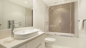 A modern bathroom with a large mirror, a freestanding sink, a toilet, and a glass-enclosed shower. - Orchid Residences Apartment 24402 (Surfers Paradise)