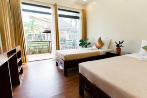 A hotel room with a balcony, two beds, a wooden dresser, and potted plants. - Asian vanda Villa  (Puerto Princesa City)