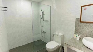 Un baño con cabina de ducha de vidrio, inodoro y lavabo con encimera de granito.