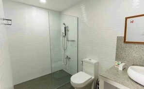A bathroom with a glass shower enclosure, a toilet, and a sink with a granite countertop. - Asian vanda Villa  (Puerto Princesa City)