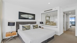 A modern hotel room with a large bed, bedside lamps, a nightstand, a mirror, and a view of the sea. - Esplanade (Soul), Apartment 5004 + 5005 (Surfers Paradise)
