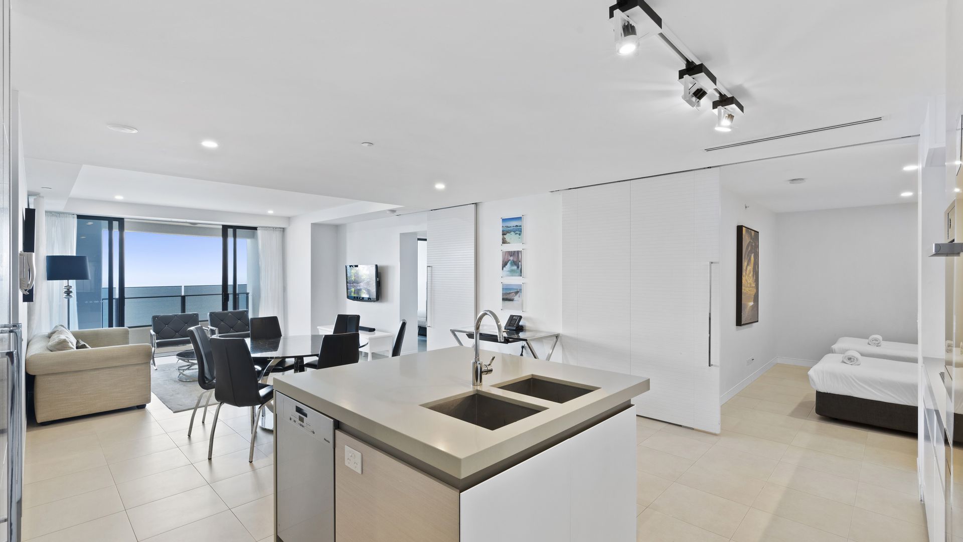 A modern hotel room with a balcony, a dining area, and a kitchen.