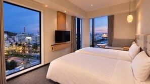 A hotel room with a large bed, a flat-screen TV, a city view, and a small table. - Hotel nostal TOKUSHIMA (tokushimashi)