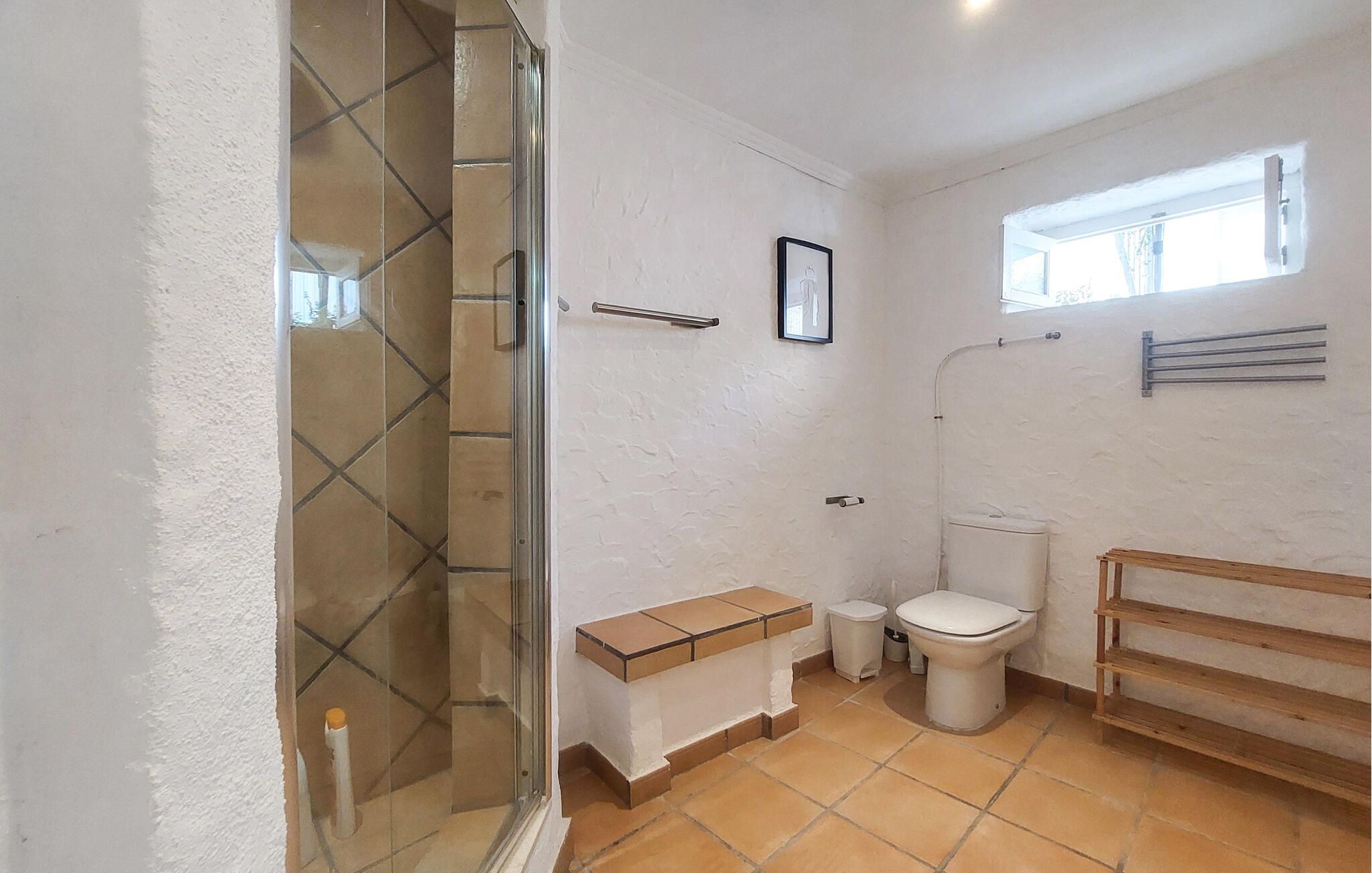 A bathroom with a shower, toilet, and a window.