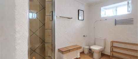 Un baño con ducha, inodoro y ventana.