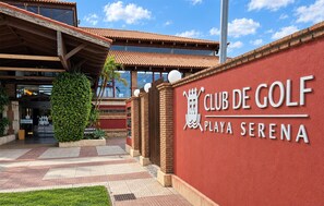 Eingang des Club de Golf mit roter Wand, einem Ziegeldach und blauem Himmel.