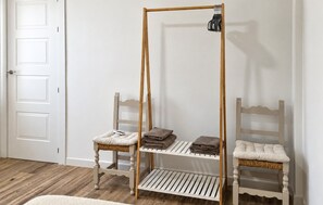 Ein Zimmer mit einer hölzernen Bank, einer weißen Tür und einem Regal mit gefalteten Handtüchern.