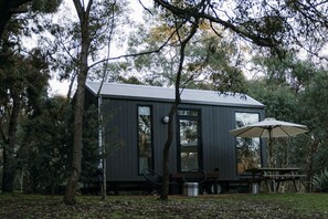 Eine moderne Holzhütte mit einem Metalldach, umgeben von Bäumen.