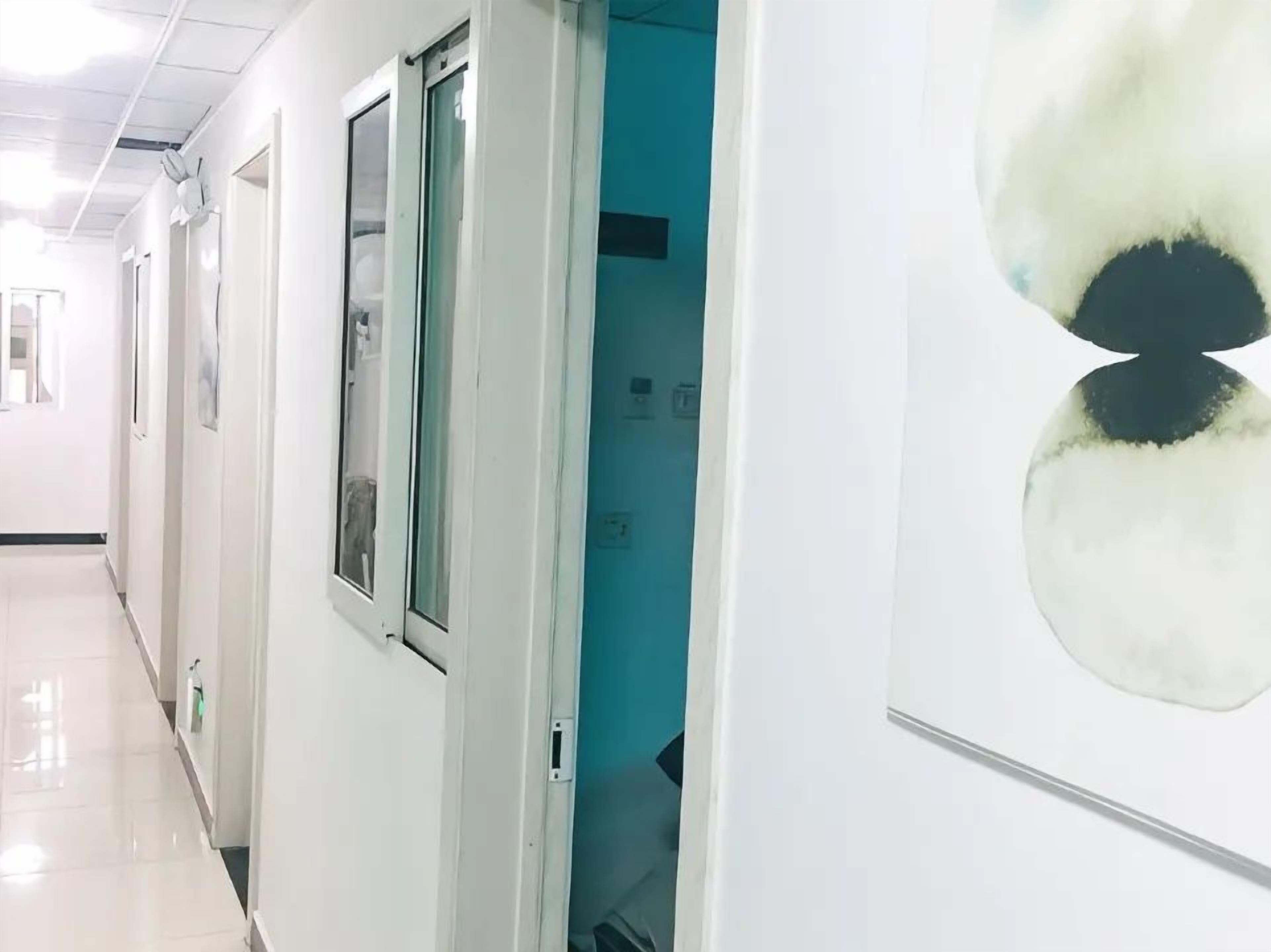 Un pasillo con puertas, una obra de arte en la pared y piso de baldosas.