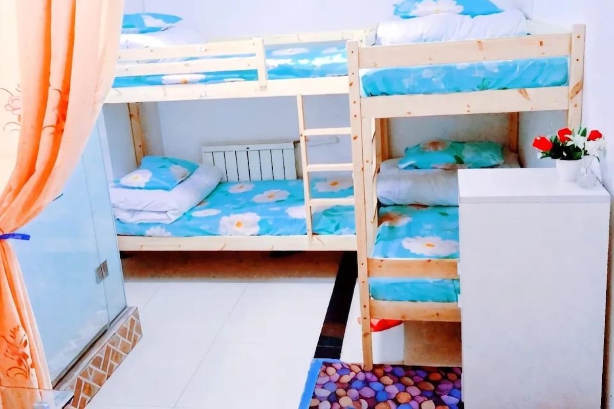 A bunk bed room with a white cabinet and a small table with flowers.