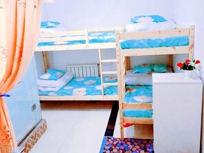 A bunk bed room with a white cabinet and a small table with flowers. - Tianjin Xinsentang Youth Hostel (Heping District)