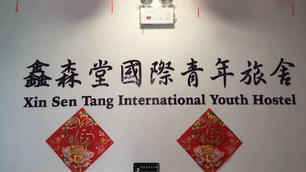 En væg med et skilt for Xin Sen Tang International Youth Hostel.