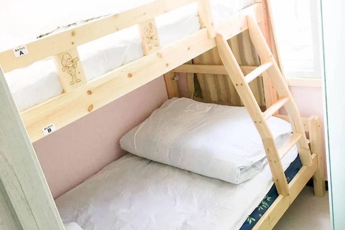 A bunk bed with a ladder, a pillow, and a tag on the side.