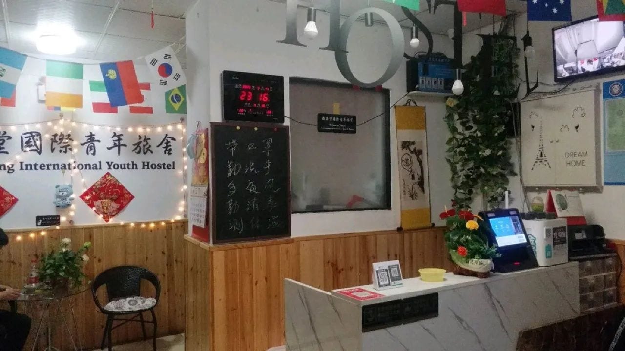 A reception desk with a digital clock, a sign with Chinese characters, and a wall with flags and a banner.