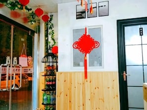 A room with a wooden wall, a shelf with bottled beverages, and a door with a sign. - Tianjin Xinsentang Youth Hostel (Heping District)