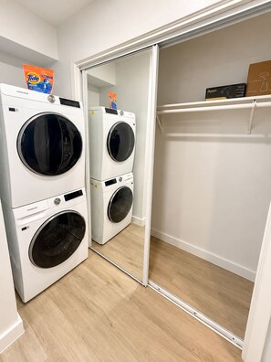 A laundry area with two front-loading washing machines and a mirrored closet door.