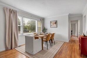 Een eetruimte met een tafel voor vier personen, een witte fauteuil en een rode kast.