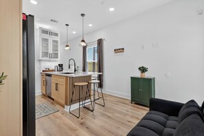 A modern kitchen with a central island, bar stools, and a green cabinet. - Upscale 2BR Getaway | Minutes to NRG & TMC (Houston)