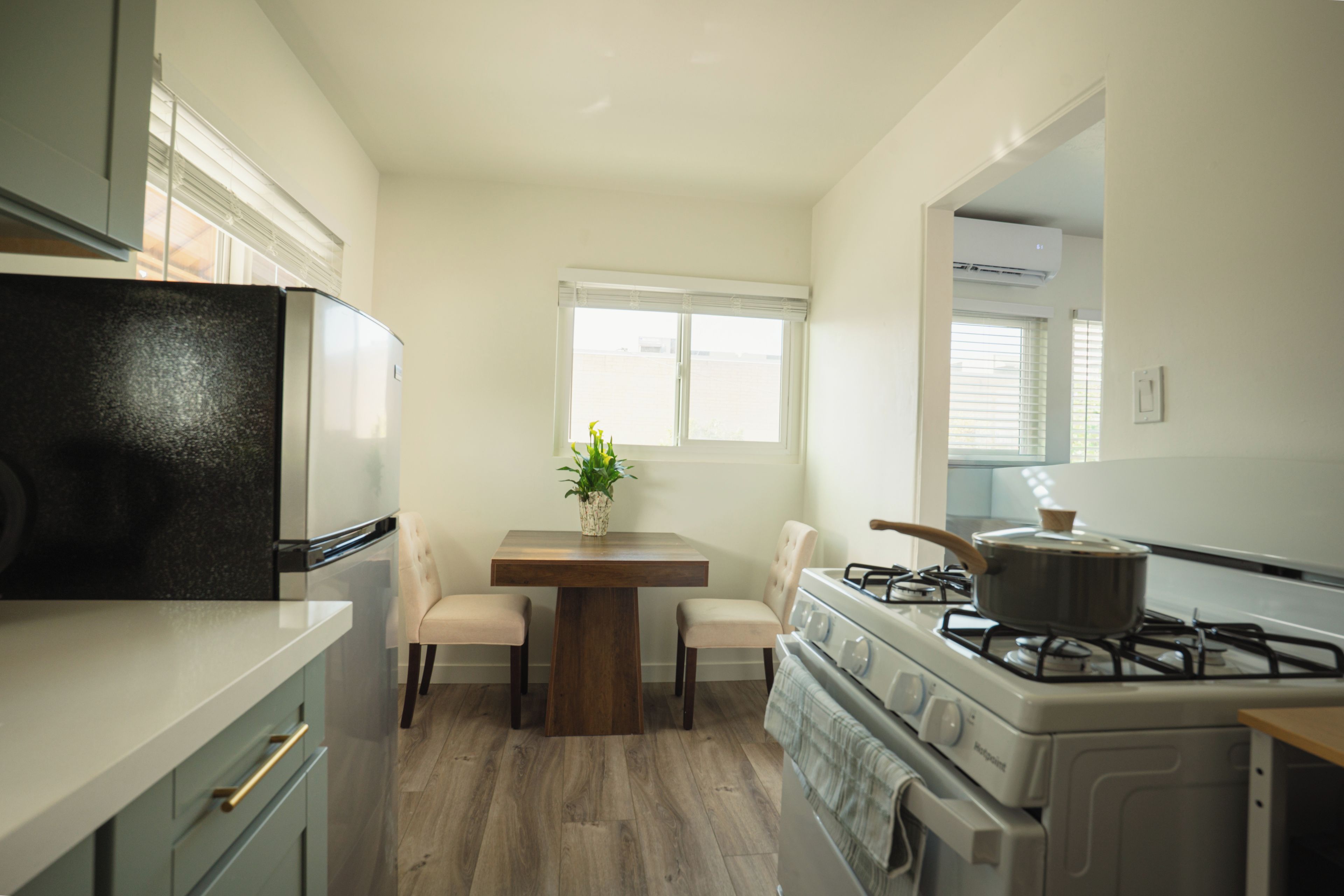 Cocina compacta equipada con refrigerador, estufa y mesa con sillas.