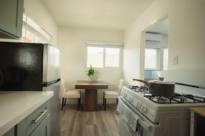 A compact kitchen with a refrigerator, stove, and dining table with chairs.