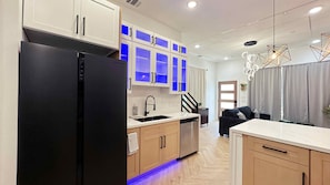 A modern kitchen with a black refrigerator, wooden cabinets, and a built-in dishwasher. - Modern 3BR for Teams, Work: Easy Highway Access (Houston)