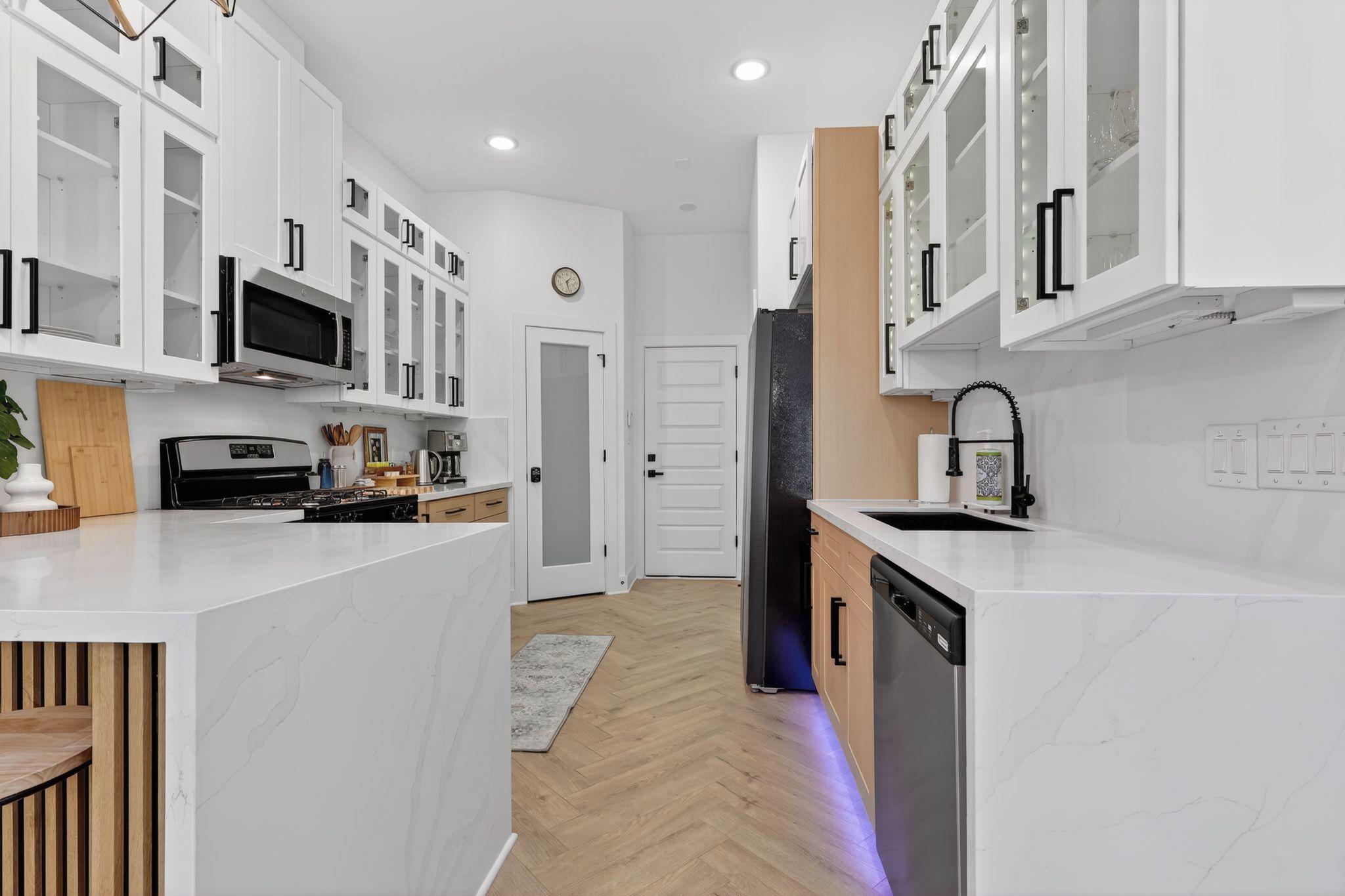 A modern kitchen with white cabinetry, a microwave, a stove, and a dishwasher.