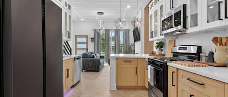 Una cocina moderna con una isla central, electrodomésticos integrados y un comedor con sofá.