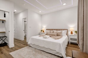 Ein Schlafzimmer mit einem großen Bett, Nachttischen, einer Wandheizung und einer Deckenleuchte.