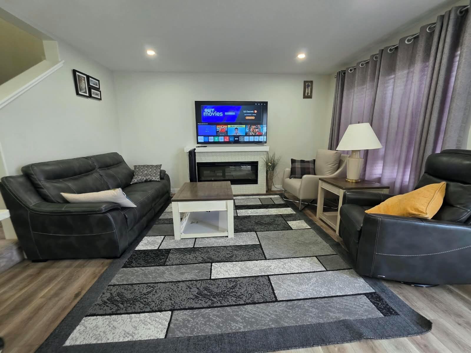 A living room with a flat-screen TV, a fireplace, a sofa, a coffee table, and a lamp.