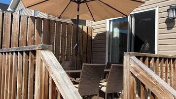 A wooden deck with a patio umbrella, wicker chairs, and a wooden fence.