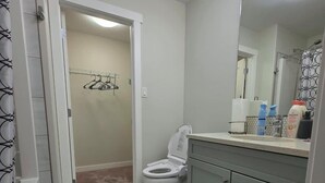 Une salle de bain comprenant des toilettes, un lavabo, un miroir et un espace douche.
