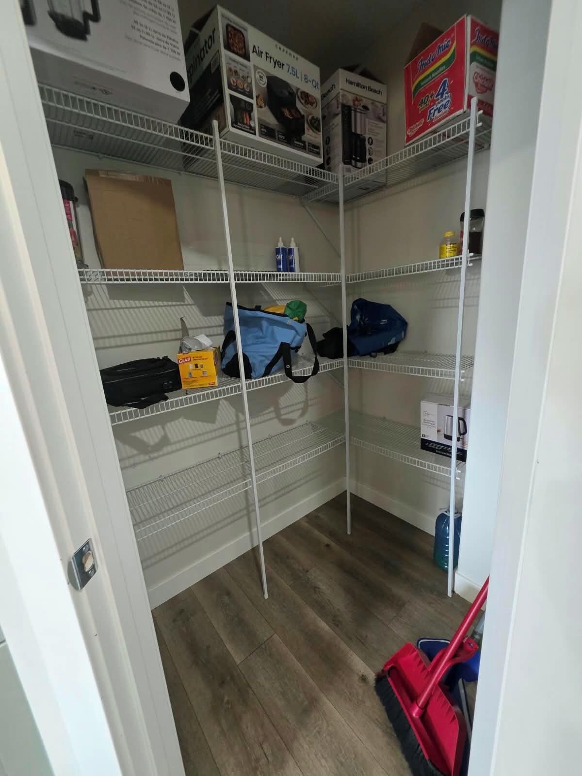 A storage area with shelves containing boxes and bags, a mop, and a water dispenser.