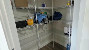 A storage area with shelves containing boxes and bags, a mop, and a water dispenser.