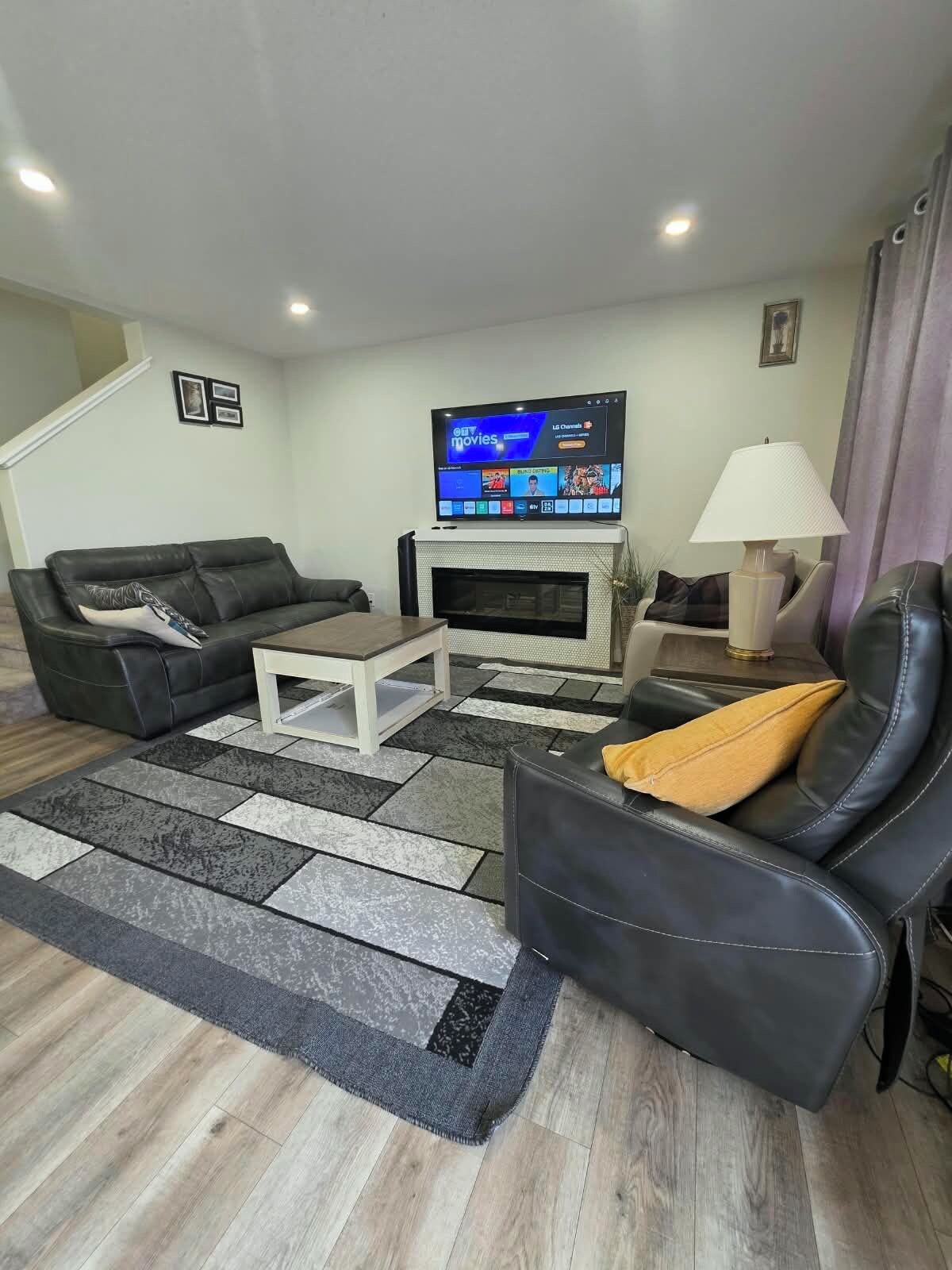 Una sala de estar con televisor de pantalla plana, chimenea, sofá, mesa de centro y lámpara.