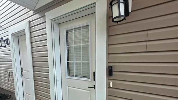 Un immeuble résidentiel doté d’une porte d’entrée, d’une fenêtre et d’un luminaire fixé au mur.