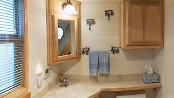 Ein Badezimmer mit einem Holzbadezimmermöbel, einem Waschbecken, einem Spiegel, einem Handtuchhalter und einer Toilette.