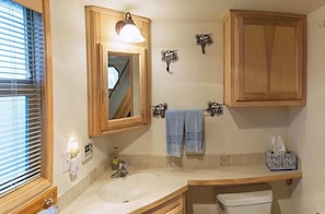 A bathroom with a wooden vanity, a sink, a mirror, a towel rack, and a toilet.