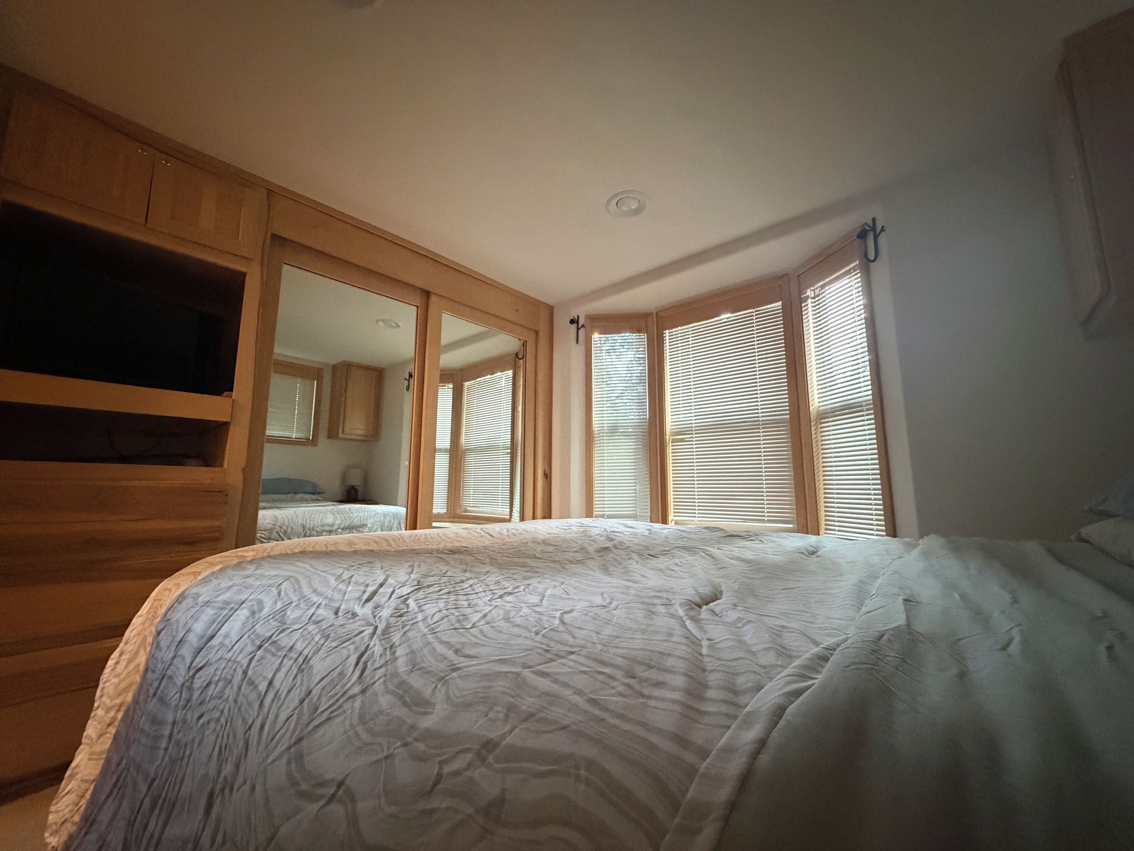 Ein Schlafzimmer mit einem großen Bett, einem Holzschrank und einer Schiebetür zu einem weiteren Raum.