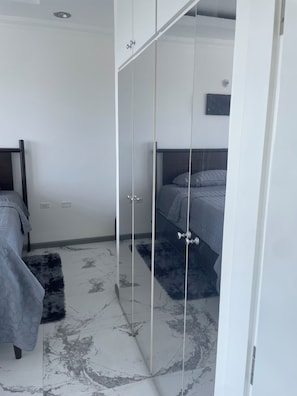 Ein Schlafzimmer mit Bett, Stuhl, Kleiderschrank und einem kleinen Teppich.