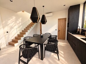 A modern kitchen with a dark countertop, wooden cabinets, and a built-in stove. - Villa Aurora By Aura (Badung)