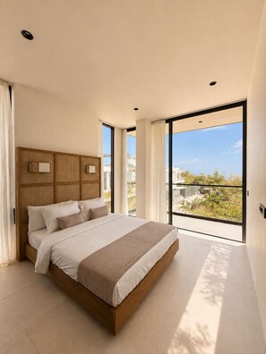 Une chambre moderne avec un grand lit, une tête de lit en bois et une vue sur l’extérieur grâce à de grandes fenêtres.