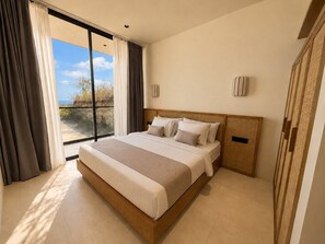 A modern bedroom with a large bed, a view of the outdoors, and a wooden headboard. - Villa Aurora By Aura (Badung)