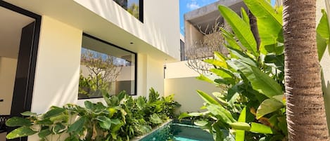 En moderne bygning med en swimmingpool omgivet af frodig vegetation.
