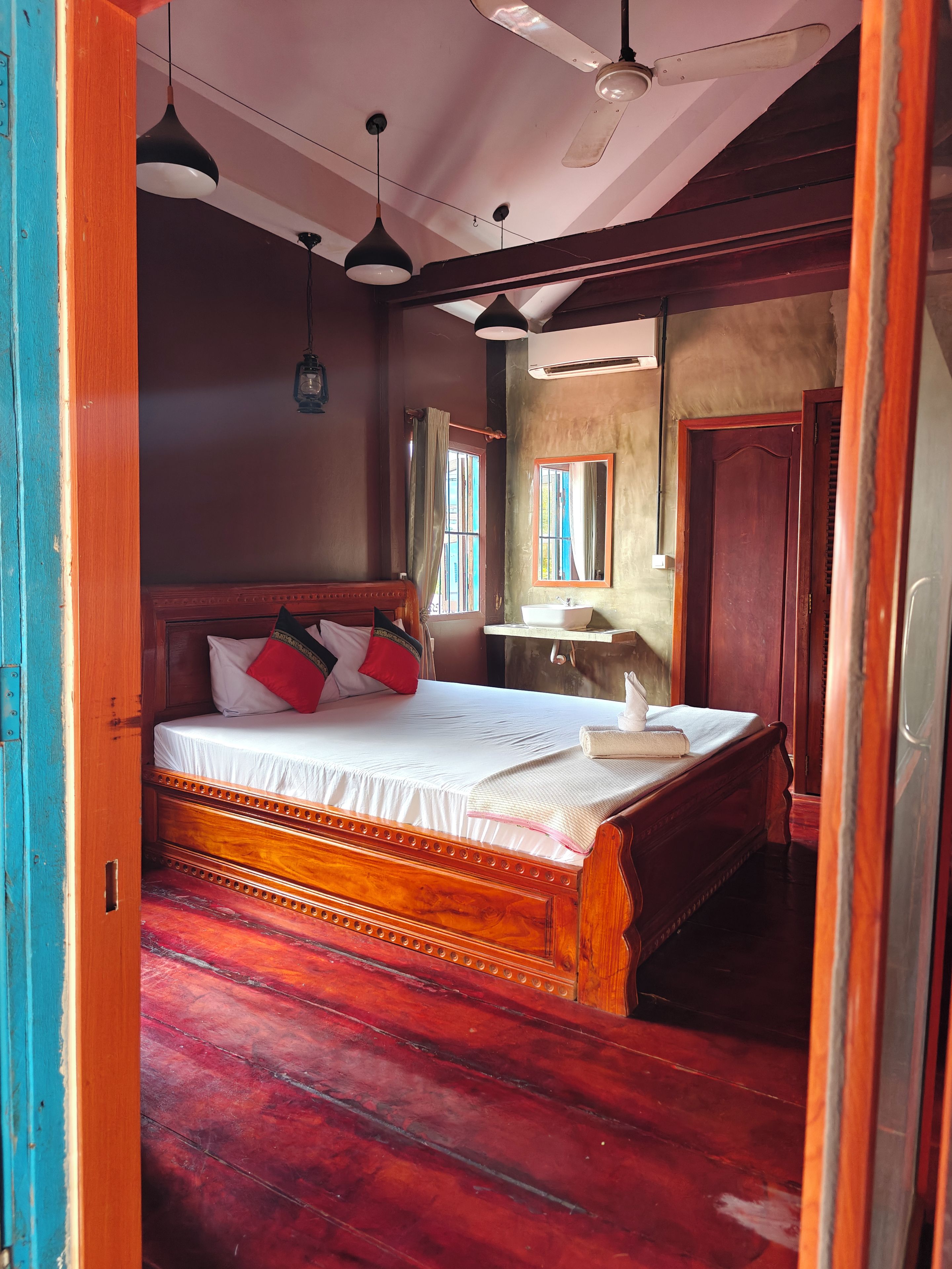 Un dormitorio con una cama de madera, una mesita de noche, un espejo y una ventana con cortinas.