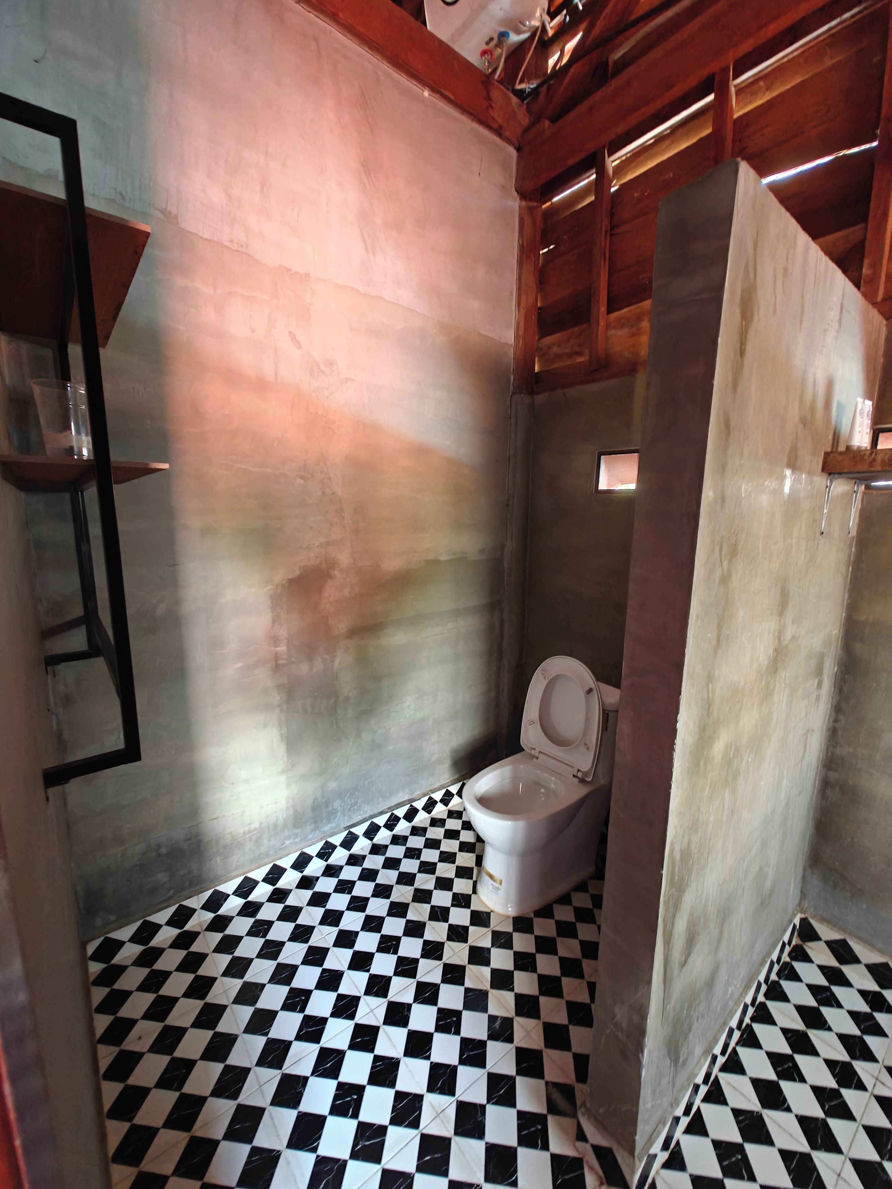 Un baño con piso a cuadros, un inodoro y un estante.