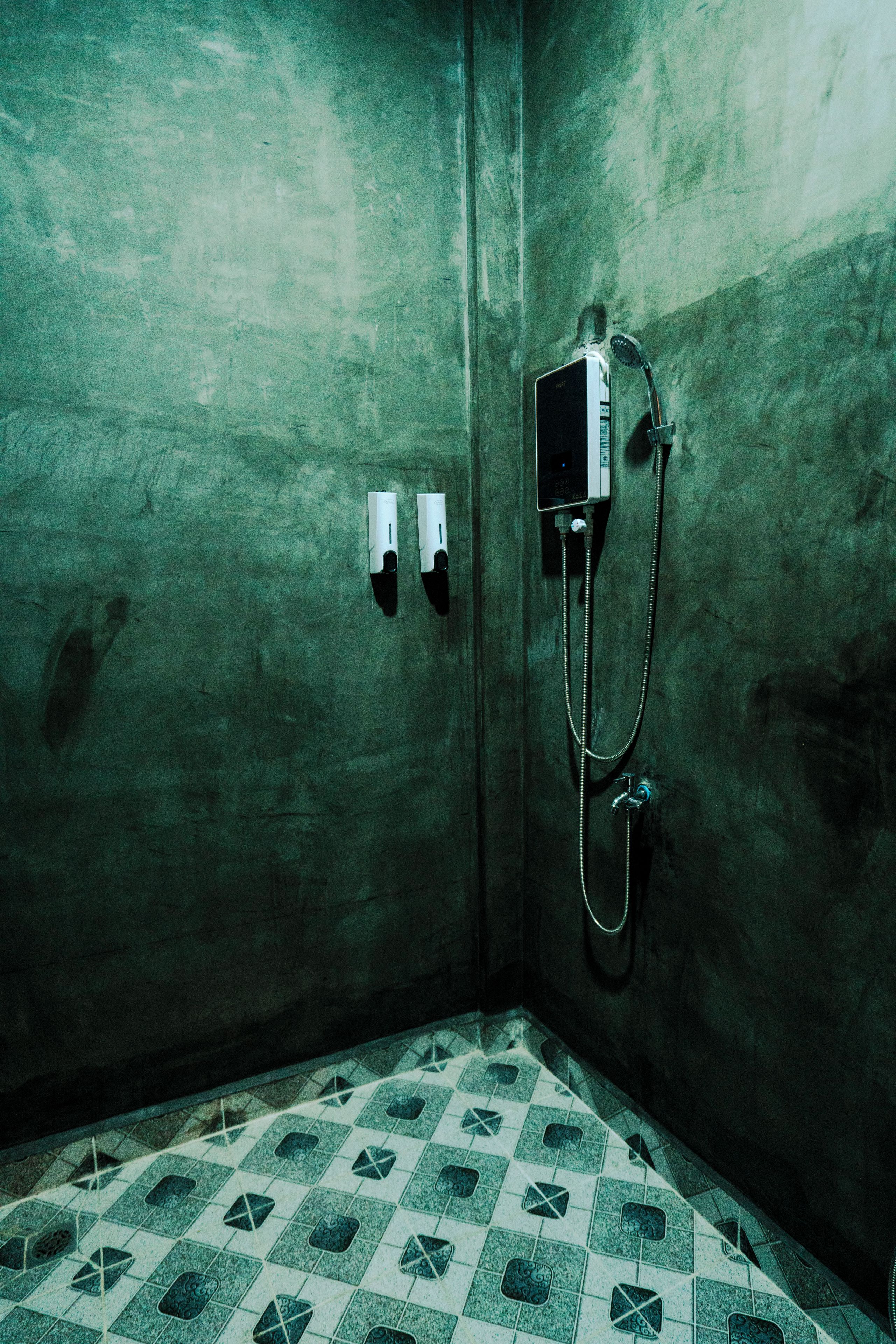 Un baño pequeño con azulejos, una ducha y dos secadores de manos empotrados.