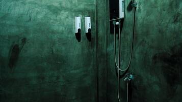 Un baño pequeño con azulejos, una ducha y dos secadores de manos empotrados.