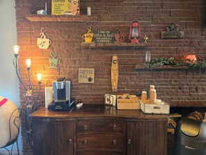 A coffee bar with a brick wall, coffee-making equipment, and various coffee-related decorations.