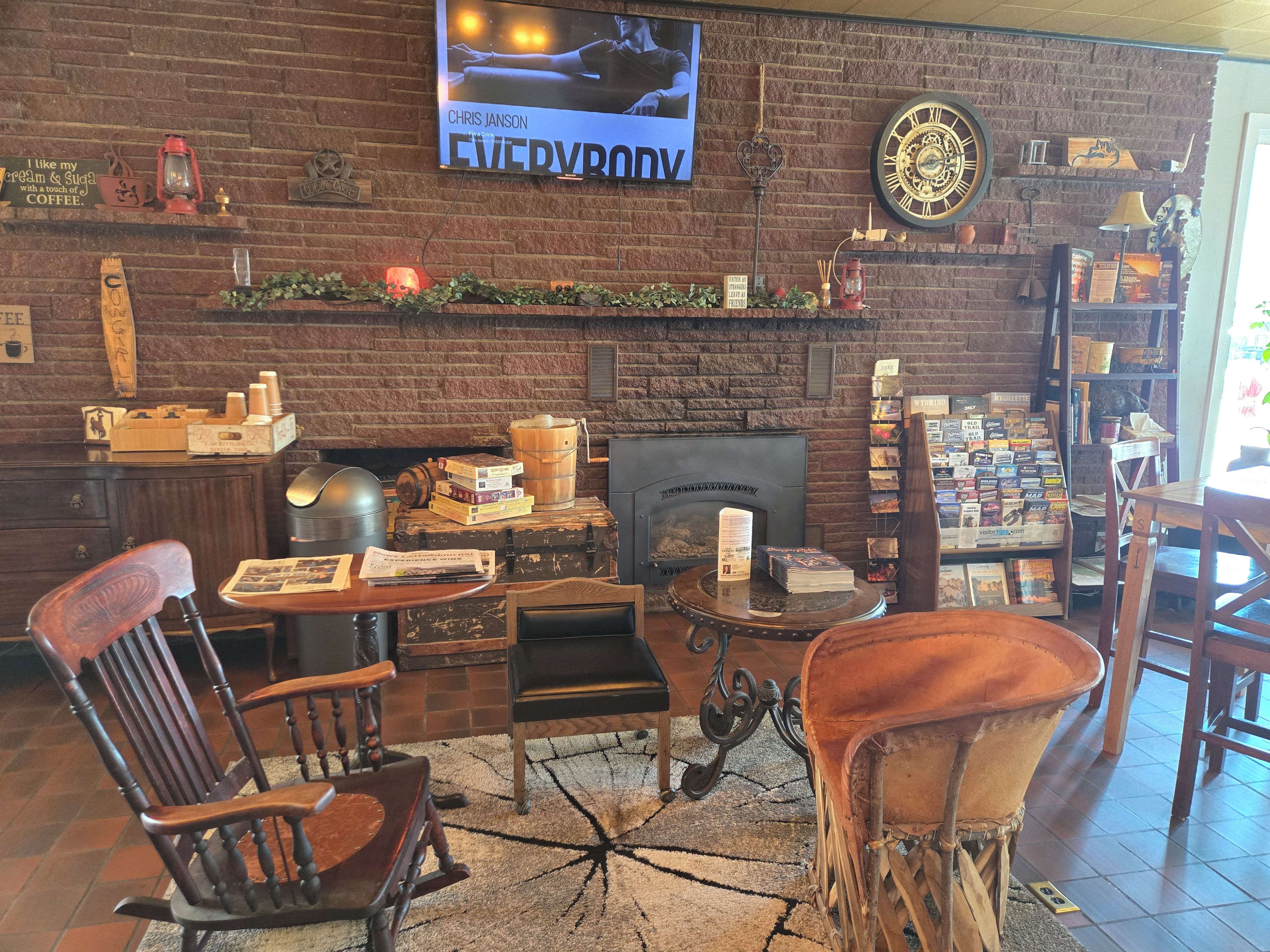 Un interior acogedor con pared de ladrillo, una pantalla de televisión, una chimenea y varios libros y revistas en estanterías.