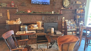 Un interior acogedor con pared de ladrillo, una pantalla de televisión, una chimenea y varios libros y revistas en estanterías.